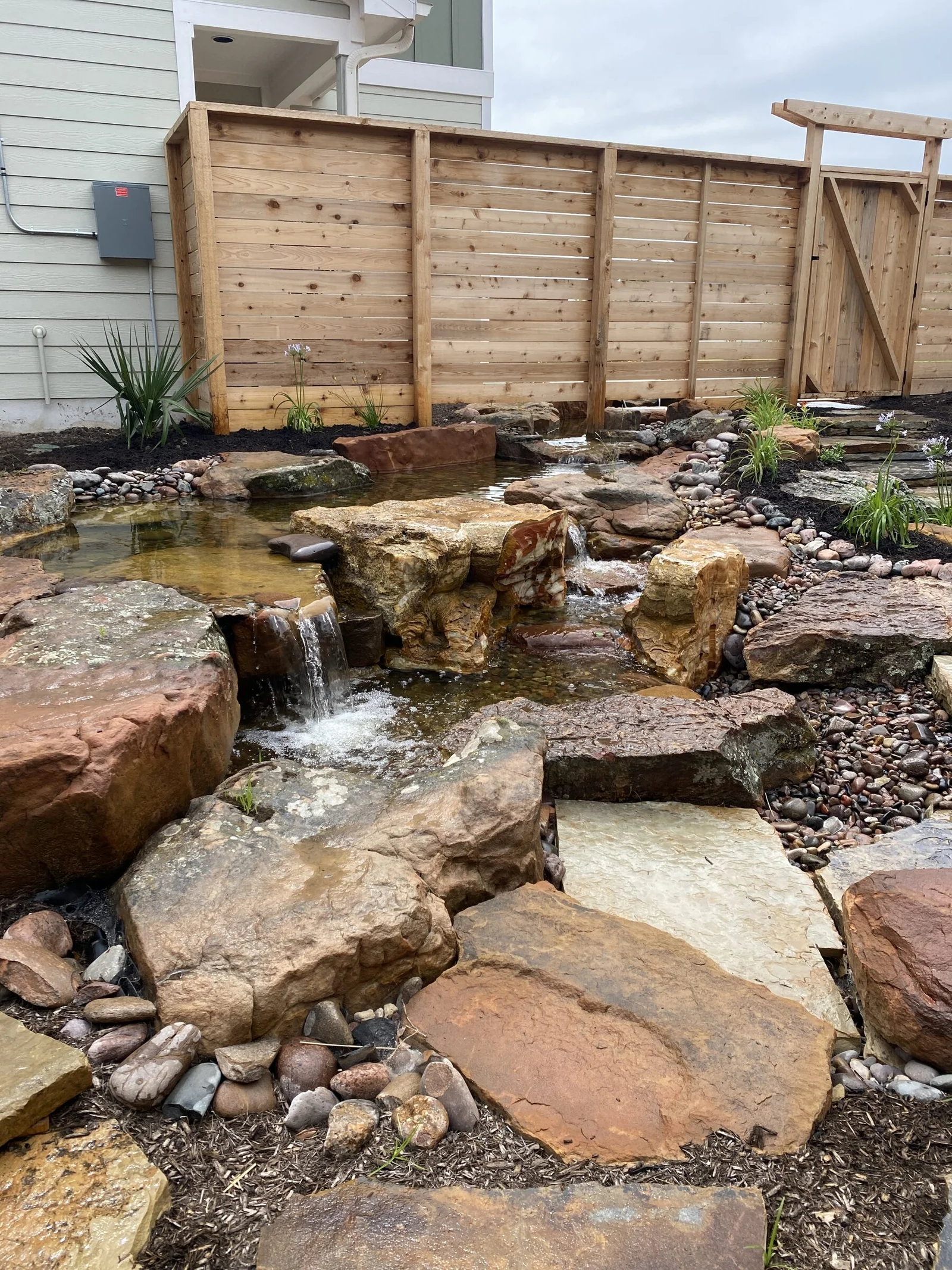 A sandstone waterfall disappearing into garden gravel