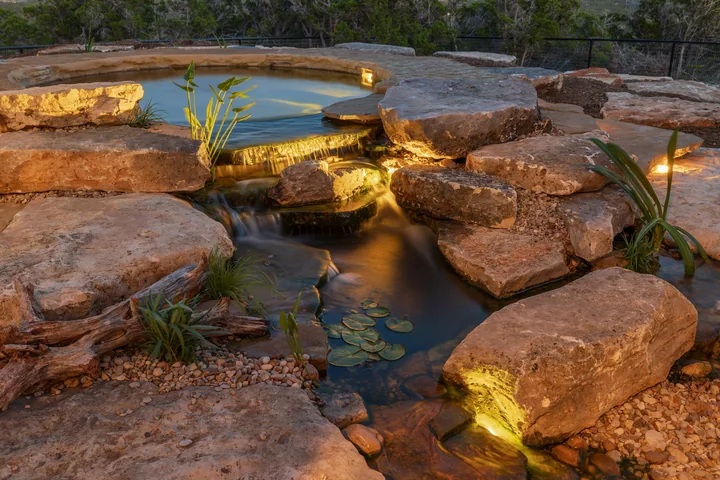 A softly illuminated stream flowing between boulders at dusk in a long exposure