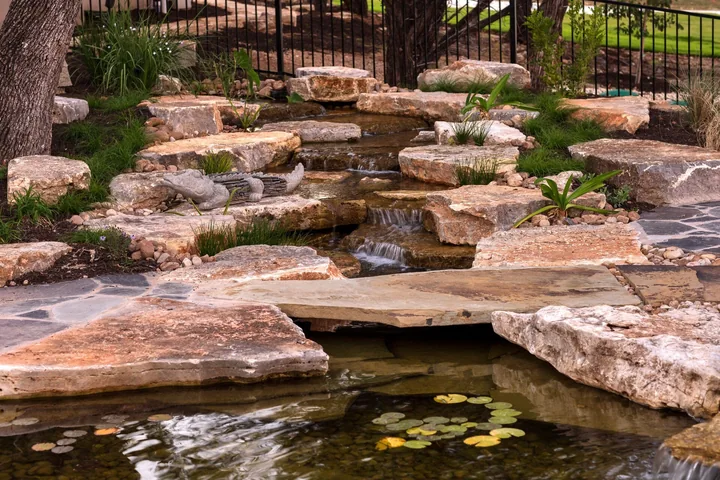 An award-winning stone pondless waterfall with water disappearing into gravel