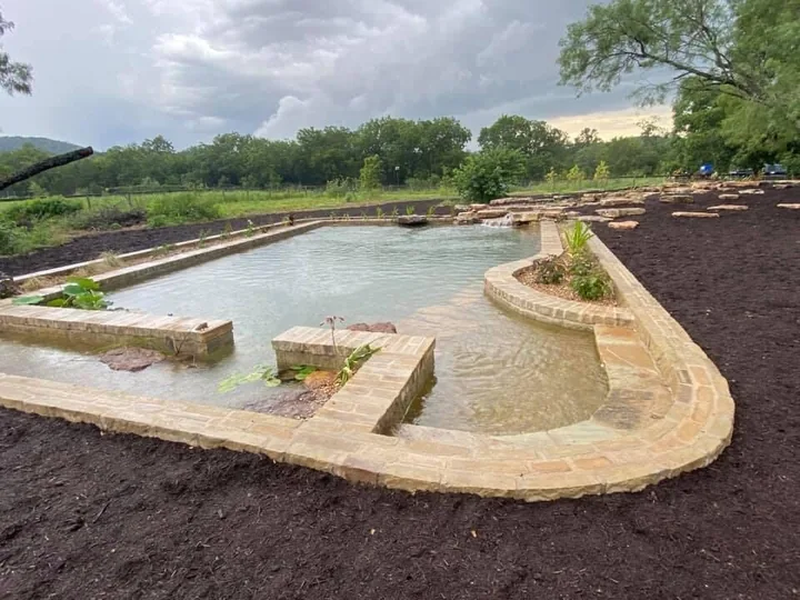 The 30 by 60 foot swim pond with a shallow entry and curved planting ledges